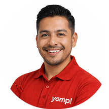 Retrato de desarrollador sonriente con camisa roja con logo Yomp sobre fondo blanco circular.